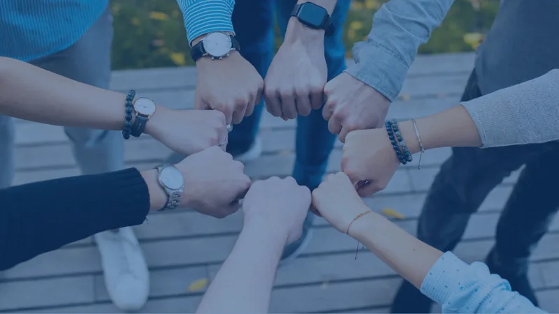 A circle of hands meeting in a fist bump