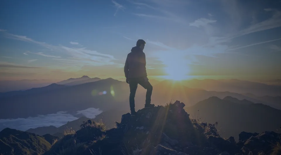 A hiker on a mountain summit at sunrise